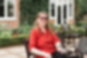 Smiling woman in red shirt sits outside