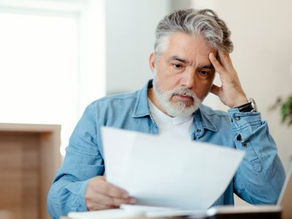 man with concern look on his face as he looks at a paper