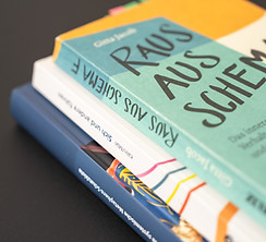 verschiedene Bücher aufeinandergestapelt - symbolisch für ein Coaching mit fundierter psychologischer Basis