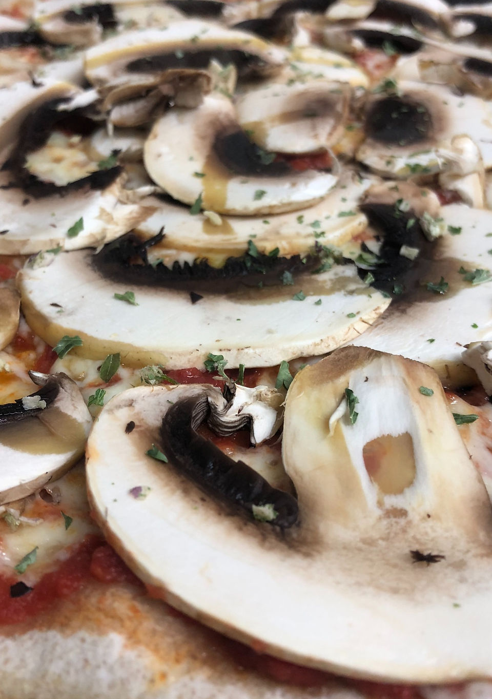 Gros plan d'une pizza garnie de champignons frais et d'herbes aromatiques, cuite à la perfection