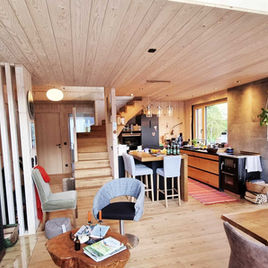 Wohnzimmer eines privaten Wohnhauses mit sichtbarer Wand- und Deckenkonstruktion aus Vollholz in Molln