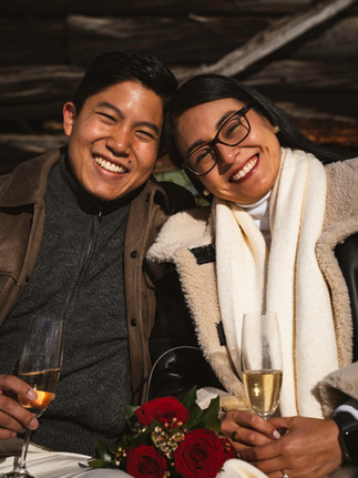 a happy couple smiles for surprise photos after getting engaged