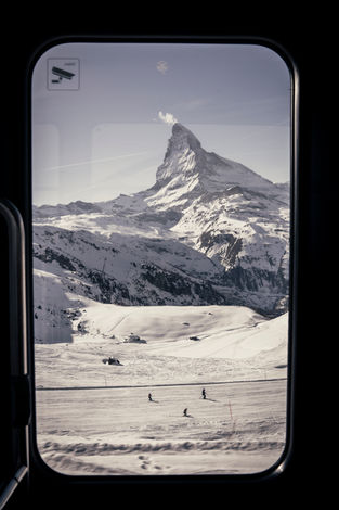 The Matterhorn and skiers through a train window