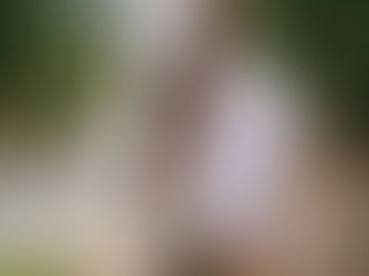 a couple holds hands back to back in gorgeous, rich colored forest. They stand alongside a stream as he closes his eyes in peaceful serenity and she holds her pregnant belly and smiles.