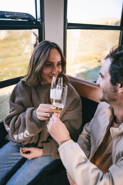 a man and woman clink glasses on the Gornergrat Train