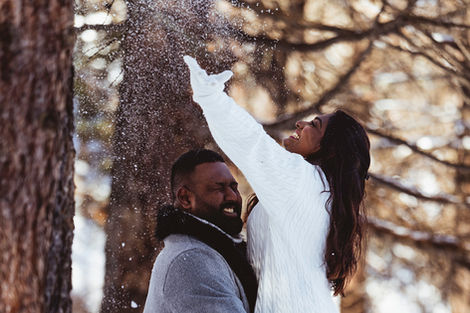 a woman playfully tosses snow above her husband