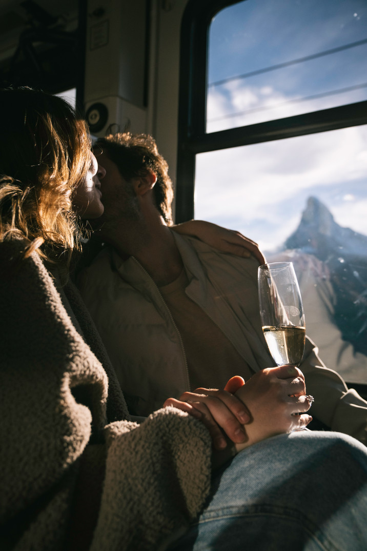a man and woman kiss on the train with the matterhorn off in the distance 