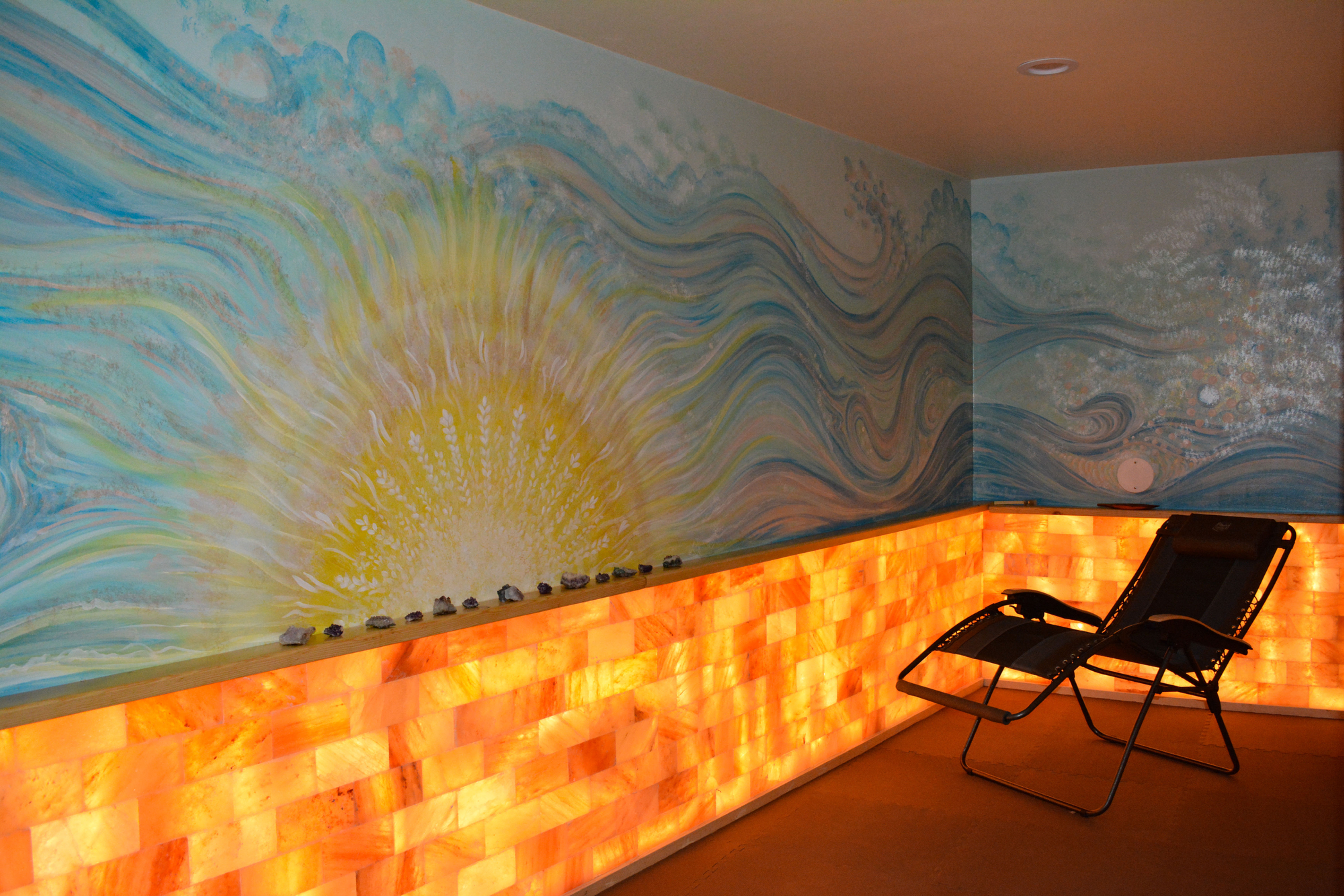 A salt room with a mural of the sun painted on the wall