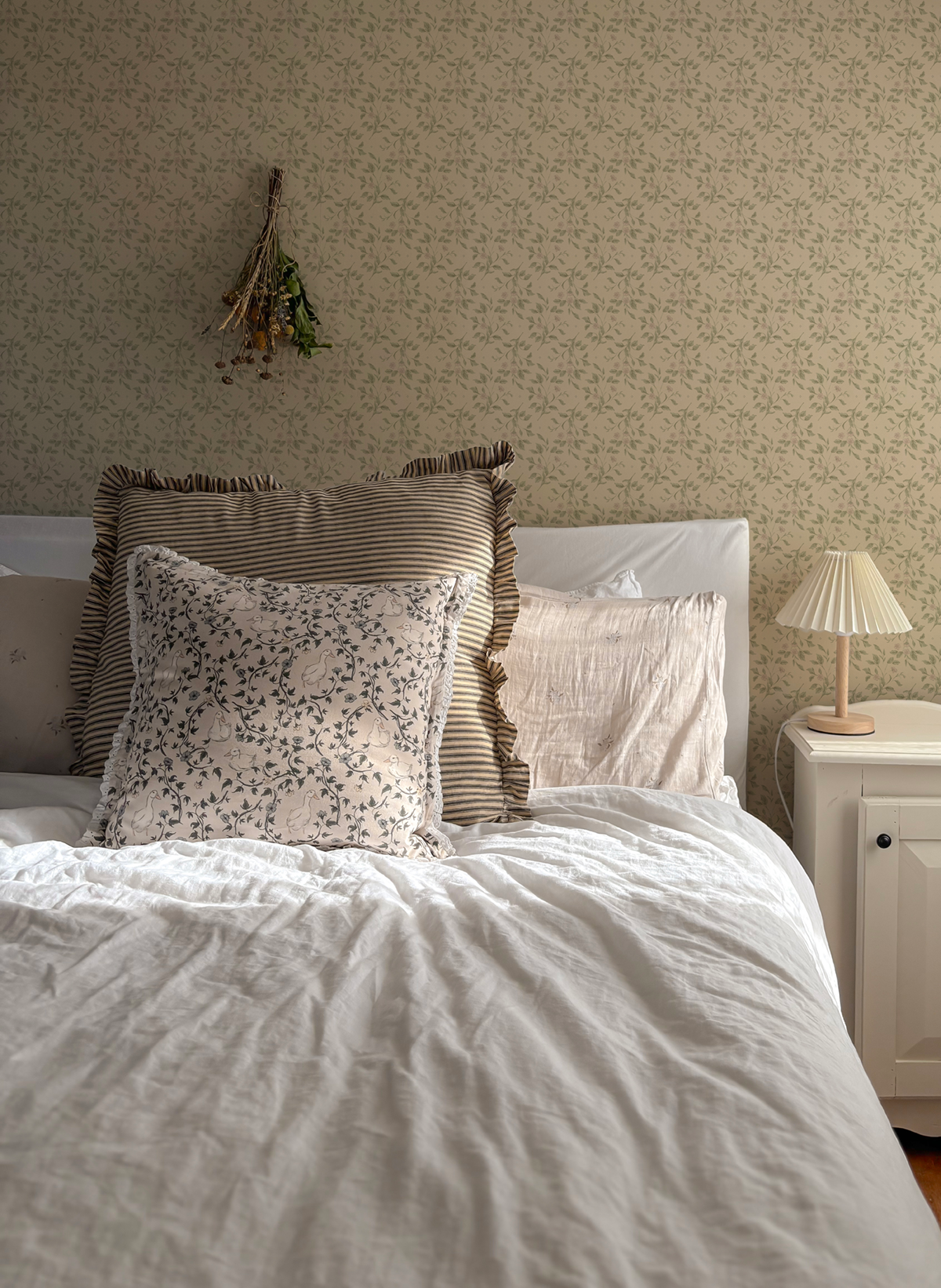 Soft trailing florals with muted green leaves and tiny blush blooms on a creamy background.