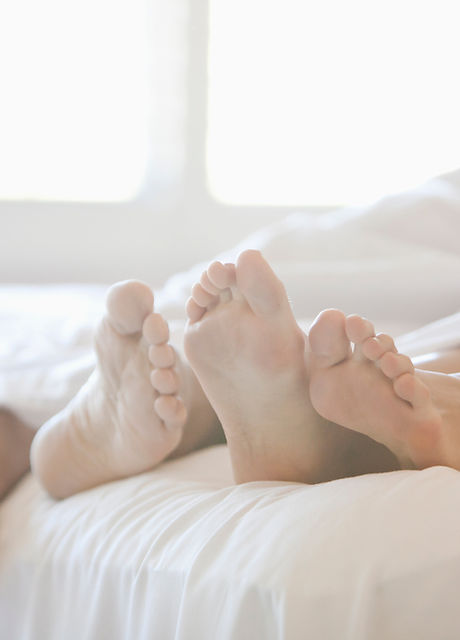 Pies del par en la cama