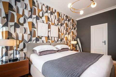 Chambre rénovée avec lit double et décoration murale géométrique à Nice