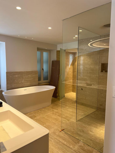 Salle de bain moderne avec baignoire blanche, douche vitrée et carrelage élégant