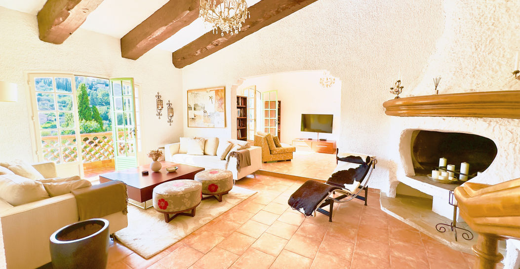 Living room with fireplace, sofas and terrace view of the villa in Saint-Paul-de-Vence