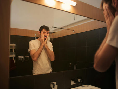 A man looking in the mirror in distress