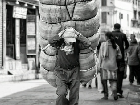 A man carrying a heavy package on his back