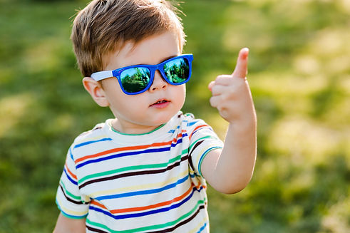 Child in sunglasses using his hands to show the number 1