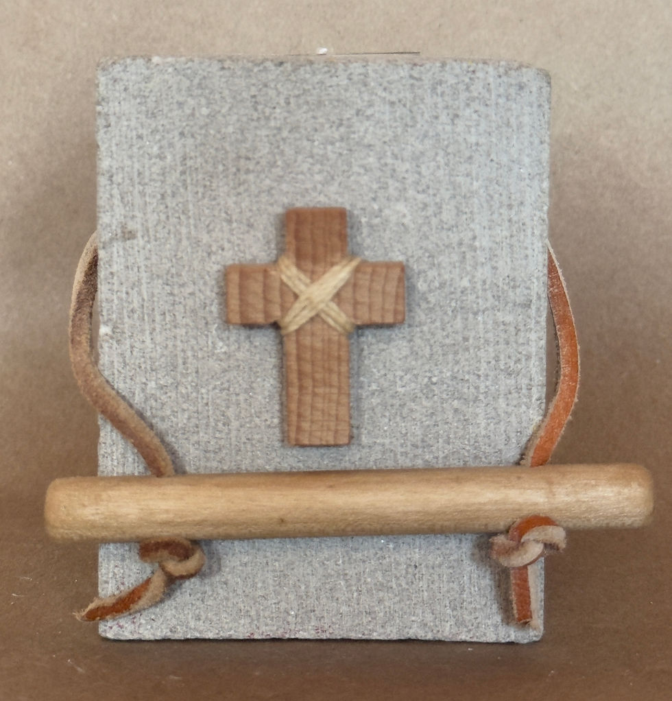 Thumbnail: A small stout Indiana lime stone sculpture with a dark brown wooden cross attached with light tan thin leather strap. 