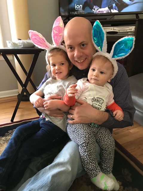 Chuck holding his two children wearing bunny ear head bands.