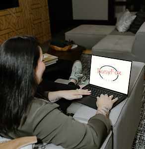 Sandy working on laptop, Busy Fox Ally logo shows on screen