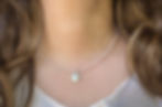 dainty pale pink rose quartz necklace with small round moon charm worn on woman at collar bone length
