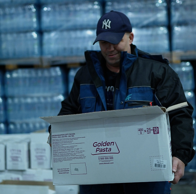 співробітник складу несе коробку з Golden Pasta