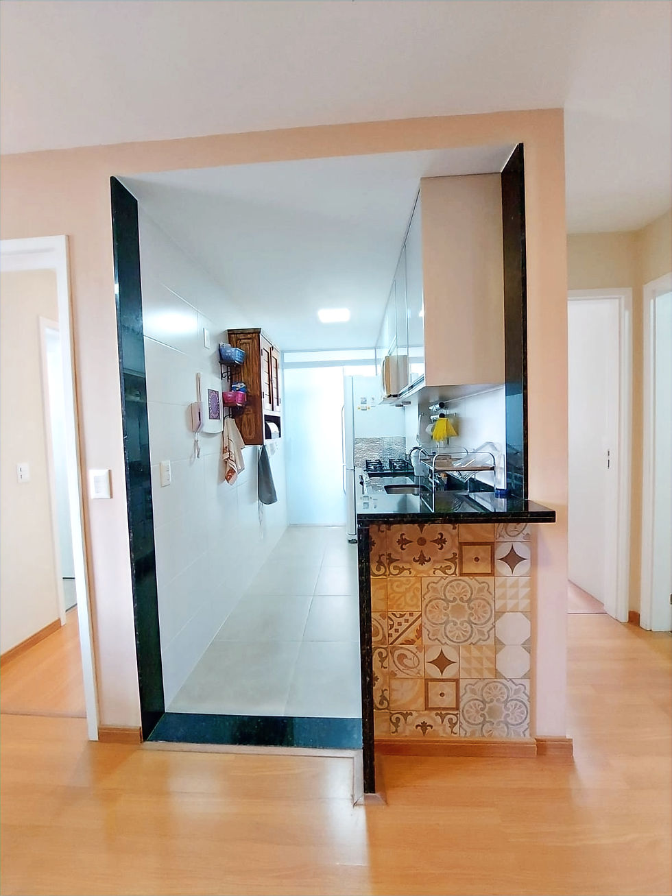 Miniatura: Cozinha integrada de apartamento com balcão e azulejos.