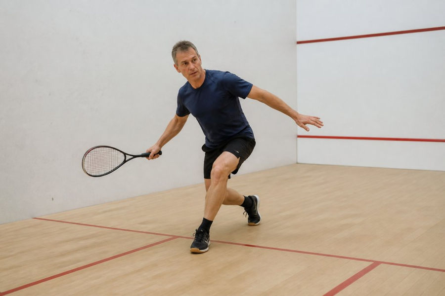 Middle-aged player practicing ghosting drills to play squash on an indoor court