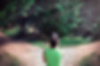 Woman standing at a fork in a forest path, symbolizing uncertainty about the future of a relationship.