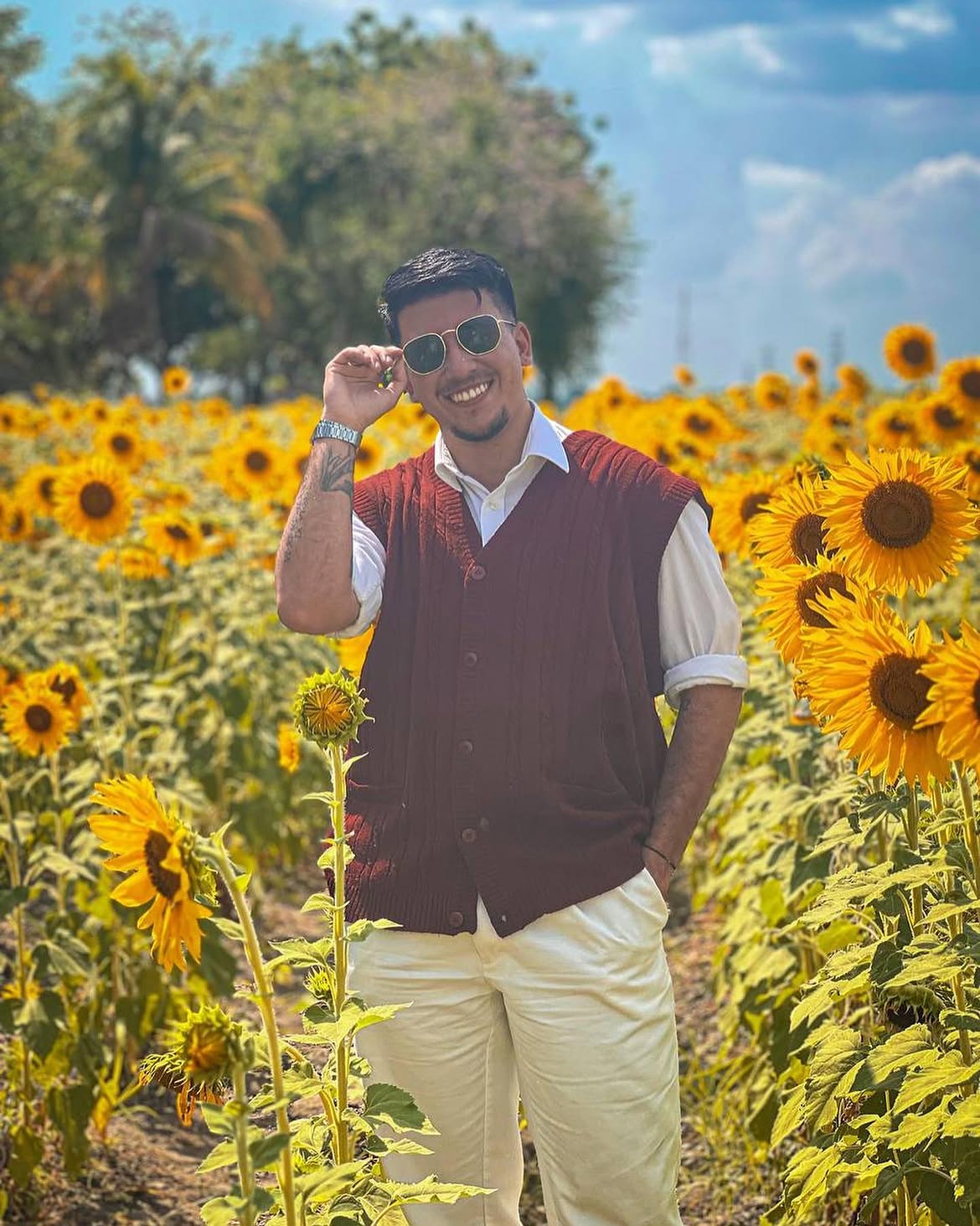 Hombre sonriente con gafas de sol en campo de girasoles