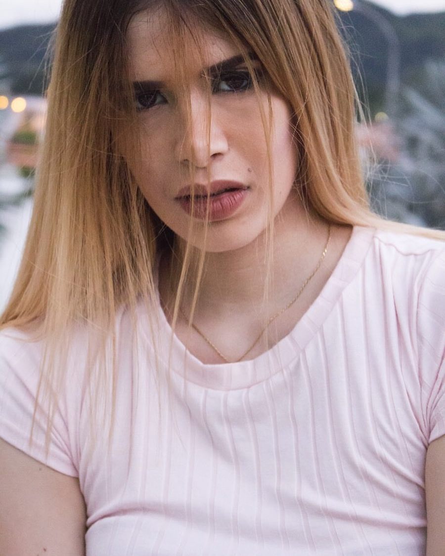 Retrato de mujer rubia con camiseta rosa en exteriores