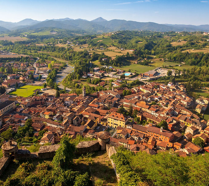 Veduta di Gavi dall’alto, con un bastione della fortezza, il borgo, la campagna coltivata e l’Appennino ligure sullo sfondo.