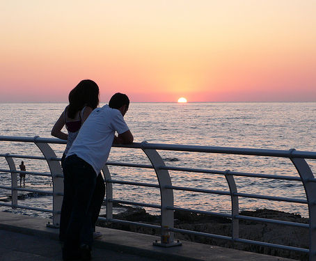 A couple watches the vibrant sunset over the Mediterranean Sea from Beirut Corniche