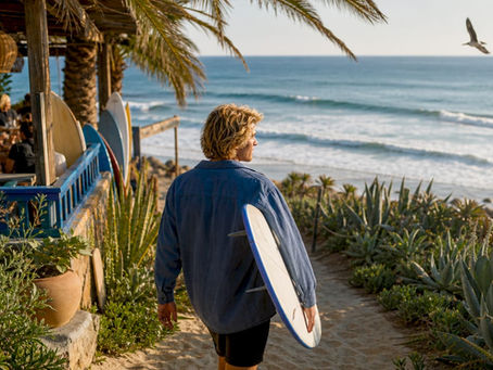 Surfer walking from beach village to ocean at sunrise