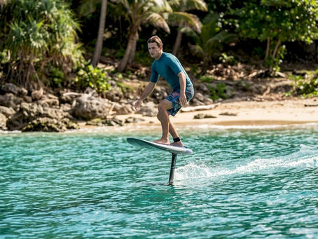 Surfer riding foil surfboard over water