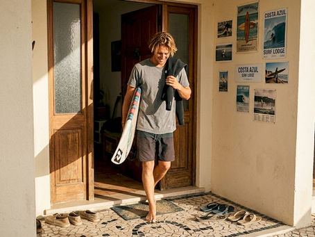Surfer entering Portugal surf lodge at sunrise