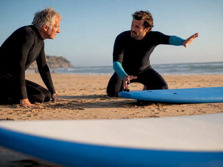Senior learner receiving surf instruction on sand
