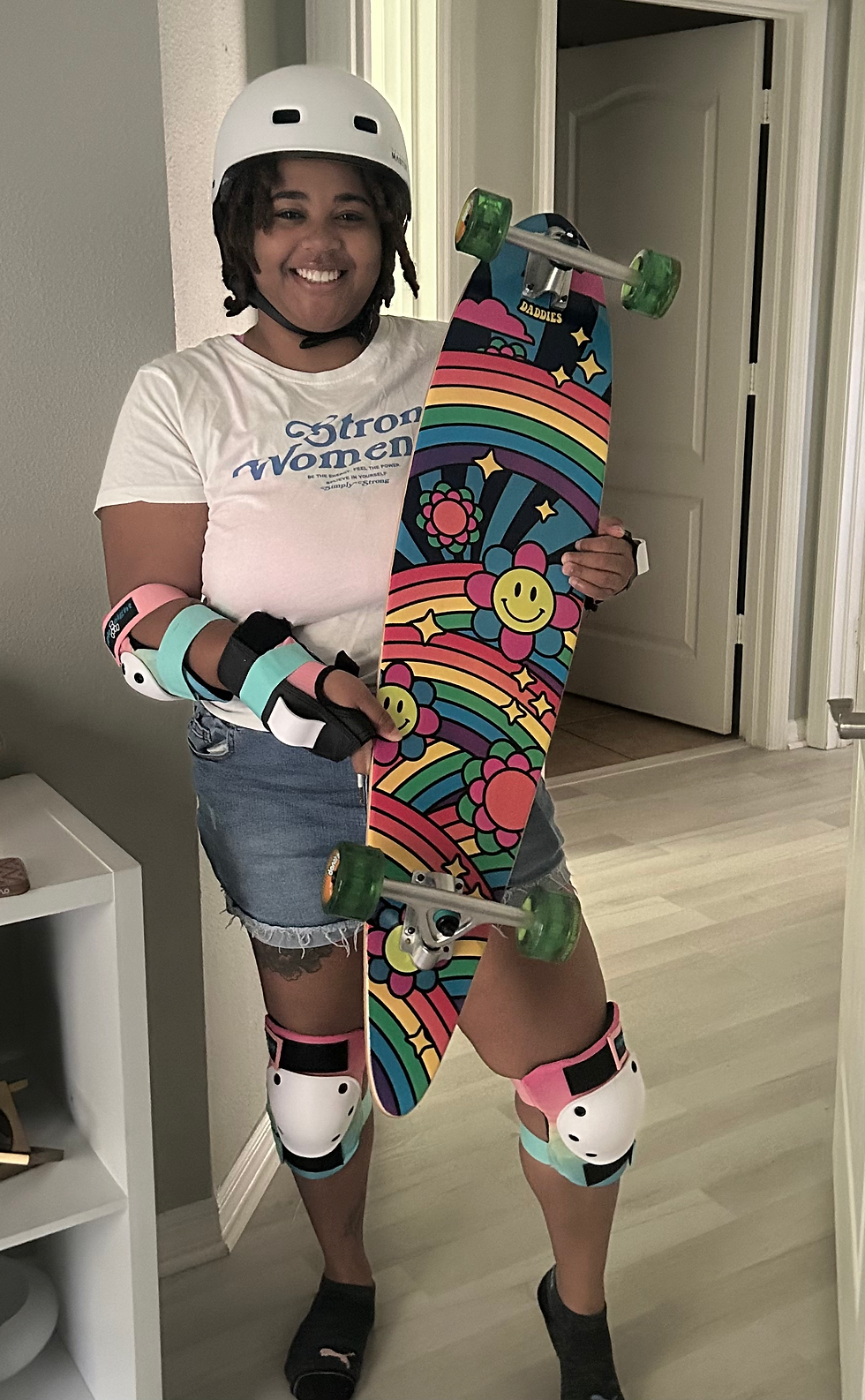 A woman with a longboard and helmet smiling.