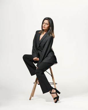 Woman in black suit sitting on stool, DHE Studio, fashion shoot.