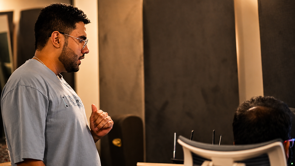 Northsinc in glasses and gray shirt speaks in a dim modern office while another person sits in foreground, focused mood