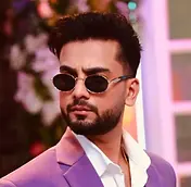 Elvish Yadav in sunglasses, wearing a purple suit, looking away from camera.