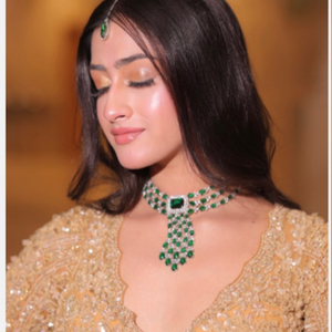 a woman wearing a necklace with emeralds and diamonds