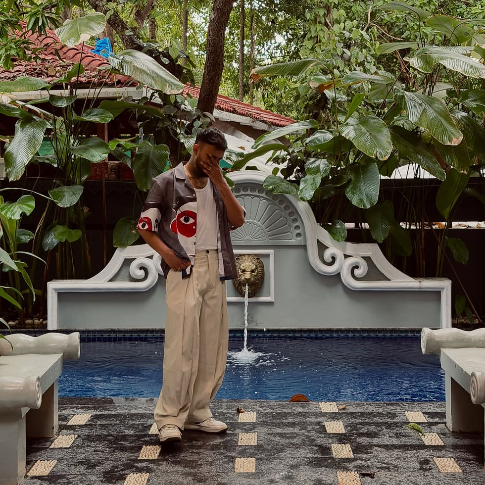 Raga posing by a small blue fountain in a lush tropical courtyard, hand on face, with a decorative lion spout and tiled floor