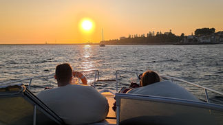 Casal a desfrutar de um cruzeiro ao pôr do sol num iate privado perto da foz do rio Douro, no Porto