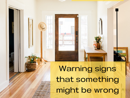 A front entryway of a home looking toward the front door. There are hardwood floors with a small rug, plants, and a hat rack