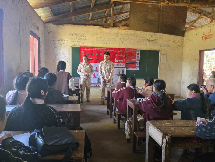 Students ages 10–14 at a local school in Phonsavan learning about unexploded bombs in their classroom. These are the same posters found in and on the sides of homes and stores throughout villages in the province.