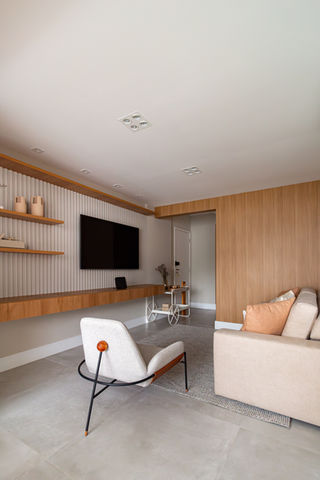 Sala de estar com painel em madeira ripada e TV embutida, reforma de apartamento de 54m² no Jardim Paulista