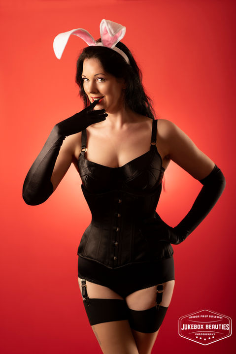 Pinup playboy bunny girl in black lingerie on red background