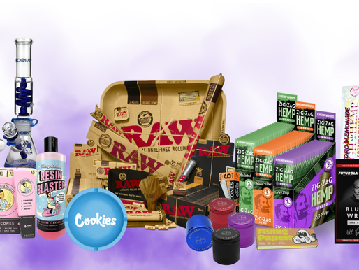 Smoking accessories display featuring glass bongs, RAW rolling tray and papers, hemp wraps, Zig-Zag products, Cookies grinder, cones, and various curated smoking tools arranged on a soft purple gradient background.