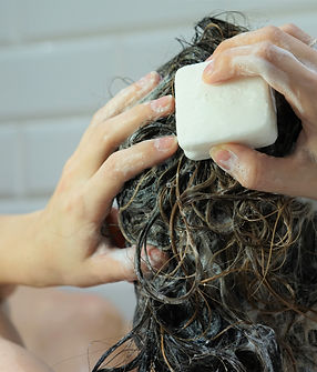 Caucasian woman washes her brown hair with shampoo bar or soap, zero waste concept.jpg