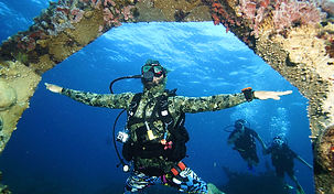 Un buzo con traje de camuflaje en Musa promocionando la página de reserva de Scuba Total Cancún.